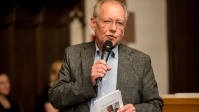 Mann hält Mikrofon in der Hand, vor dem Mund und redet