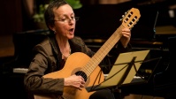 Frau singt und spielt Gitarre