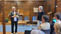 Zwei Frauen in einer Kirche, ene Frau hat einen Blumenstock in der Hand