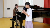 Eine junge Pianistin und ein Mädchen, das Blockflöte spielt