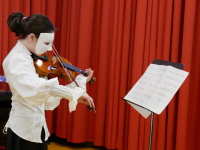 Mädchen mit weißer Karnevalsmaske, das Geige spielt